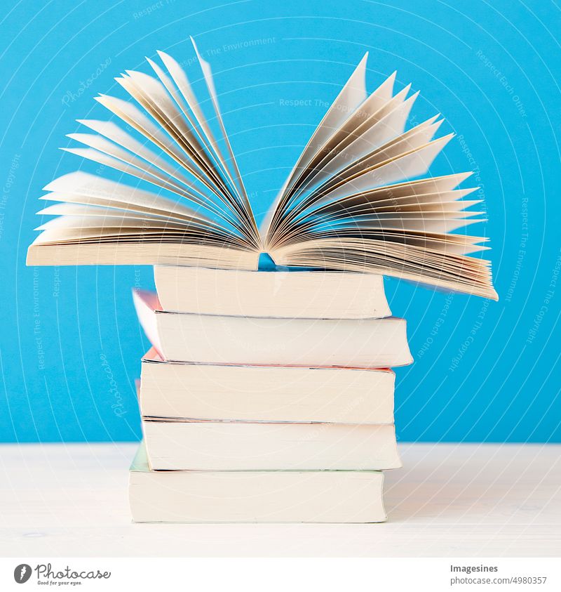 Stack of books. open book with nostalgic rose - tea hybrid "Augusta Luise". Rose flower on blue background Reading Education Literature Study School Advertising