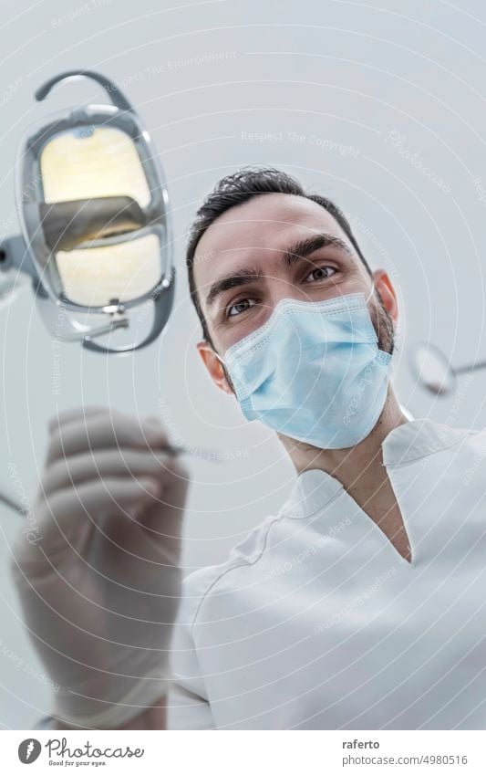 Low angle view of male dentist in medical mask holding dentist tools for dental procedure in clinic Dentist person stomatology dentistry low angle glove closeup