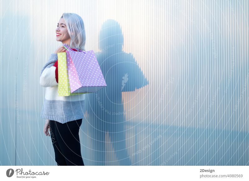 Portrait of young happy smiling woman with shopping bags blond carrying retail happiness toothy standing smile consumerism female holding shopaholic cheerful