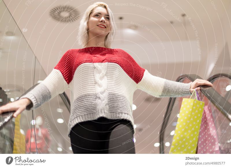 Portrait of young happy smiling woman with shopping bags on a escalator buy customer elegant indoors moving positive purchase retail sale station store stylish