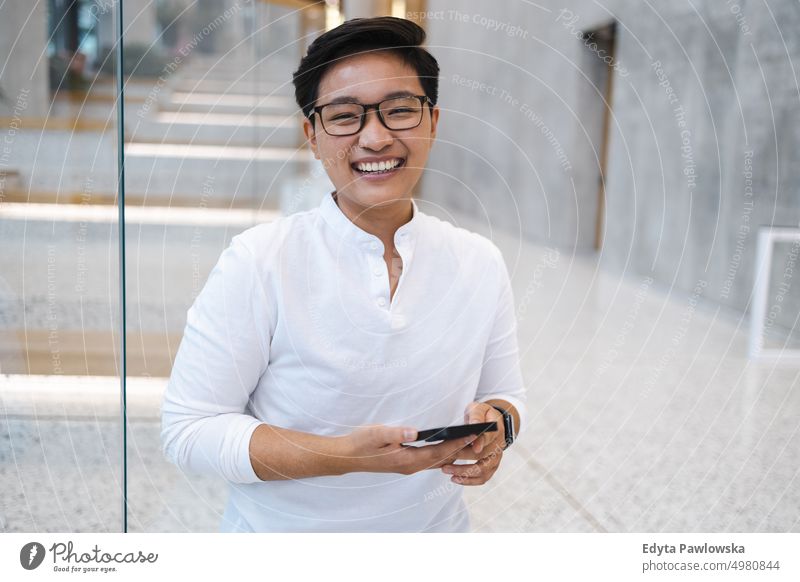 Smiling young man using mobile phone real people natural young adult city urban student positive smile cheerful career confident successful business person