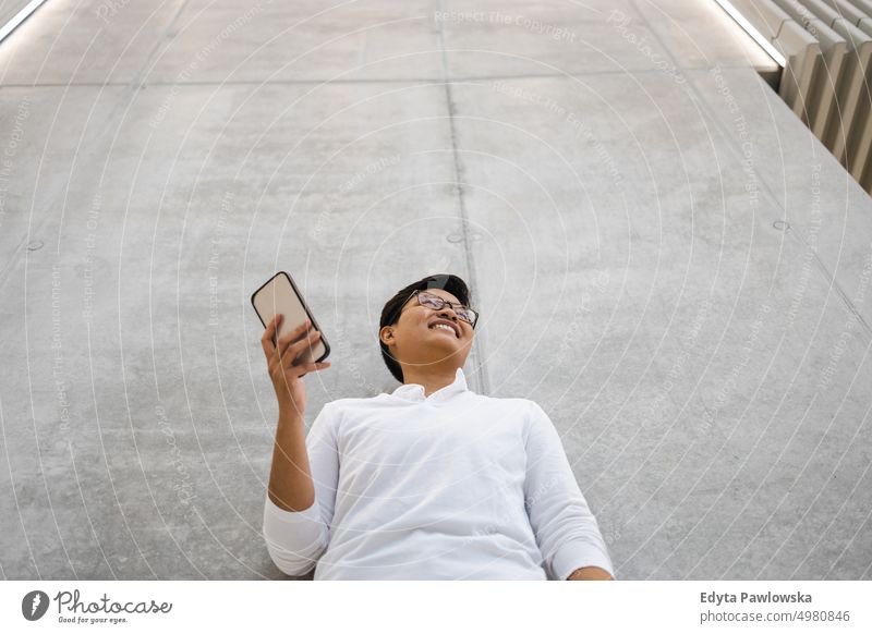 Smiling young man using mobile phone real people natural young adult city urban student positive smile cheerful career confident successful business person