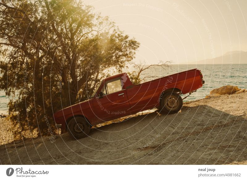 Red pickup truck parked on sloping road in front of sea horizon in warm evening light Landscape car Pick-up truck Easygoing Parking Parking lot Steep mountains