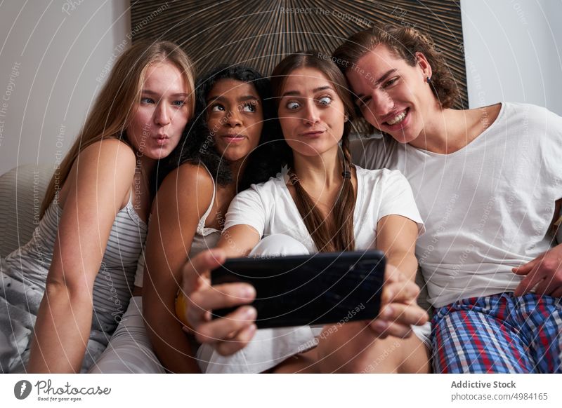 Grimacing multiethnic friends taking selfie at home make face grimace flatmate joyful smartphone cheerful self portrait together happy using photography