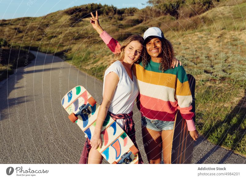 Women friends walking down the road holding skate boards women portrait skateboard skater countryside fun woman beautiful young trendy stylish skateboarder