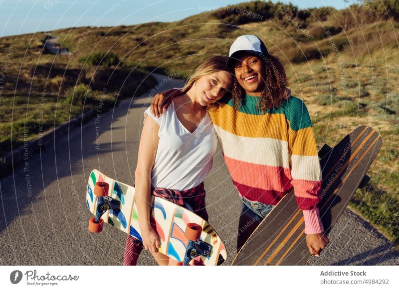 Portrait of women friends looking at camera portrait skateboard skater road countryside fun street woman beautiful young trendy stylish skateboarder lifestyle