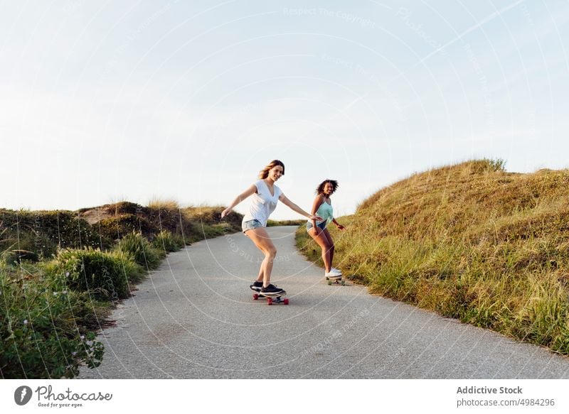 Beautiful women skater friends riding on road woman skateboard countryside fun street beautiful young trendy stylish skateboarder lifestyle girl summer female