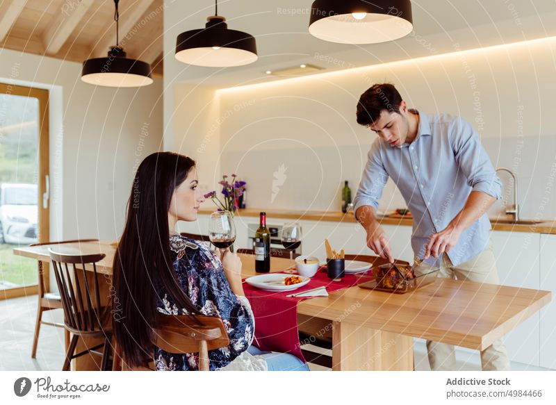 Happy couple dinning at table in kitchen serving happy hispanic eating plate glass wine smiling woman young attractive cheerful beverage dinner drink meal