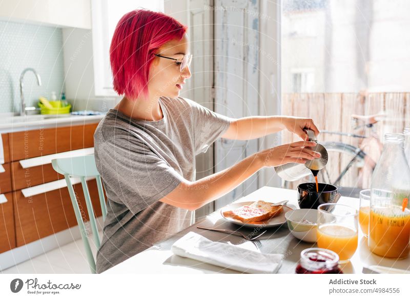 Young female pouring coffee for breakfast woman morning home smile mug coffeemaker young dyed hair drink beverage cheerful rest relax apartment lifestyle