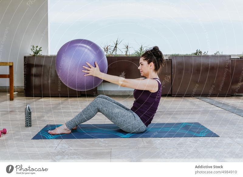 Flexible sportswoman doing sit-ups with fit ball on terrace stretch exercise pilates wellness training balance vitality wellbeing flexible fitness female young