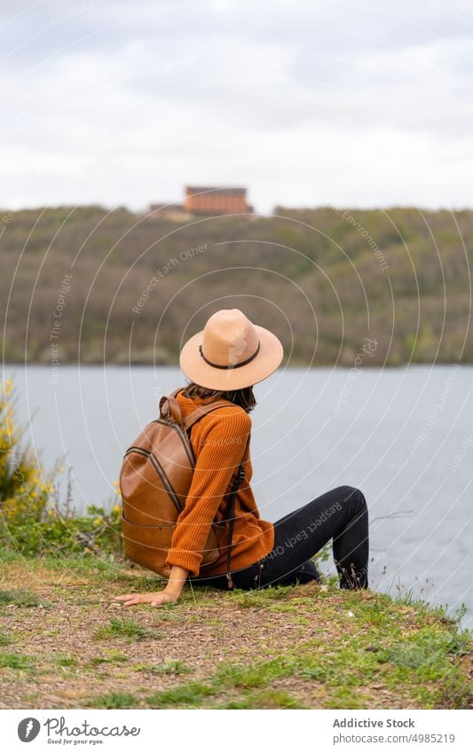 Anonymous woman with backpack on shore of river traveler river bank summer vacation chill female palencia spain nature tourist journey weekend water adventure