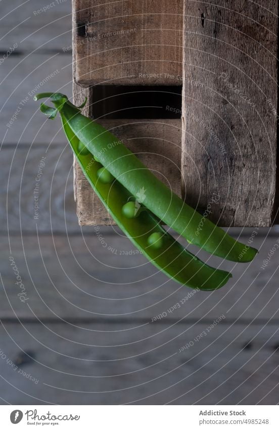 Closeup of pea pod on wood green fresh vitamin food vegetable organic open plant legume nutrition row seed raw harvest vegetarian ingredient grain health vegan