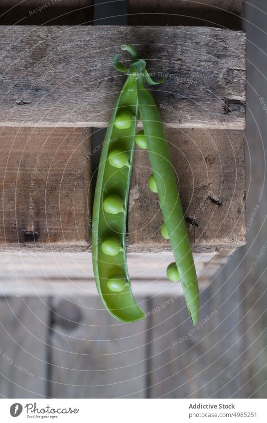 Closeup of pea pod on wood green fresh vitamin food vegetable organic open plant legume nutrition row seed raw harvest vegetarian ingredient grain health vegan