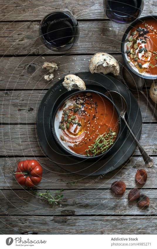 Served soup in bowls on table with vegetable cream tomato served layout seeds apricots wood dried delicious meal bread nutrition buns traditional cutlery