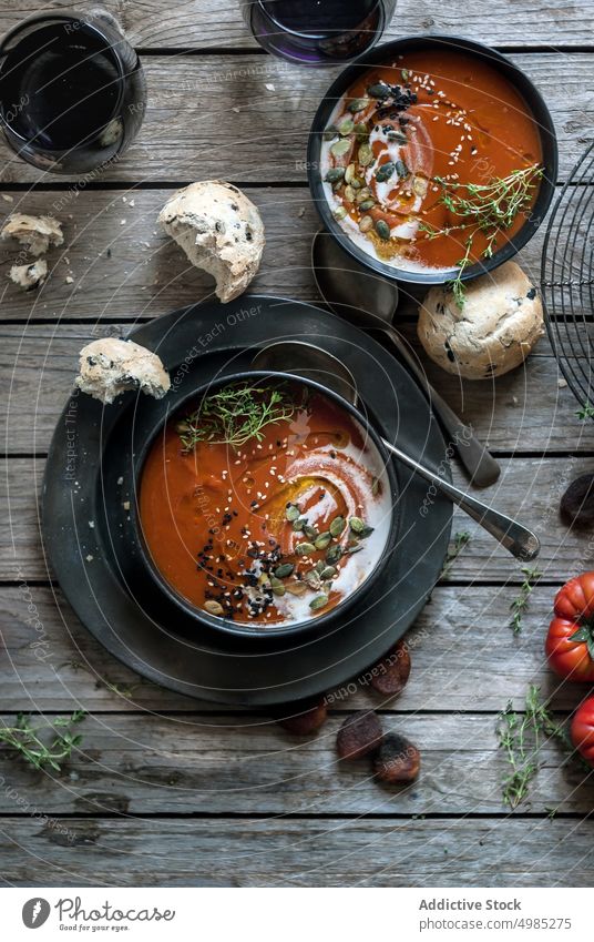 Served soup in bowls on table with vegetable cream tomato served layout seeds apricots wood dried delicious meal bread nutrition buns traditional cutlery