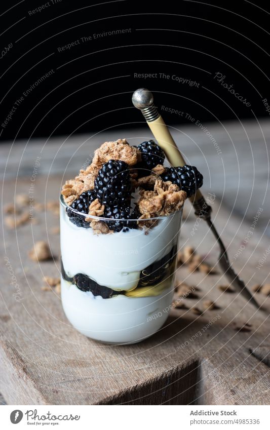 Glass full of walnut granola with blueberries glass blueberry yogurt mix board wooden cutting chopping jar ripe pile fresh food delicious healthy natural diet