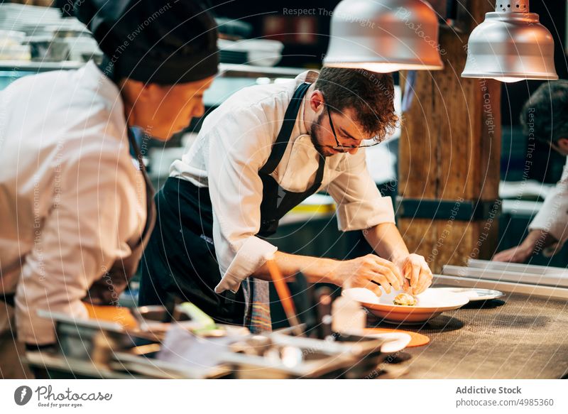 Coworking cooks serving food on counter serve kitchen woman restaurant occupation indoors professional culinary design row gourmet teamwork interior cuisine