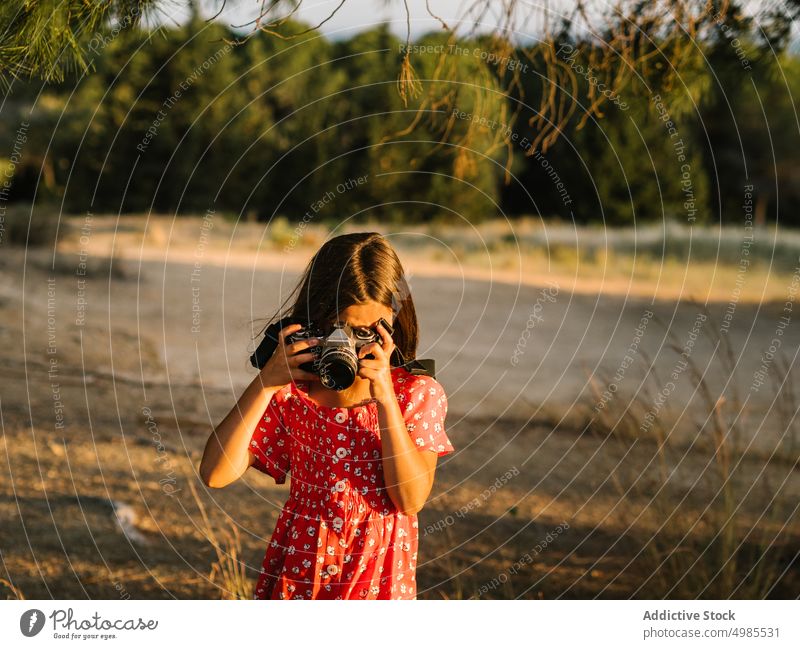 Little girl taking photo of landscape in sunny day summer field nature camera photography happy meadow beautiful adorable red child enjoyment device dress ears