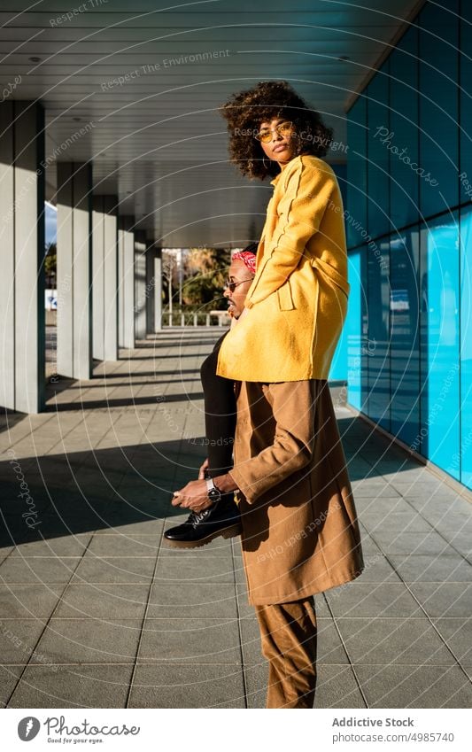 Cool back man carrying girlfriend on shoulders in city couple street style trendy urban fashion tall colorful ethnic black african american happy together