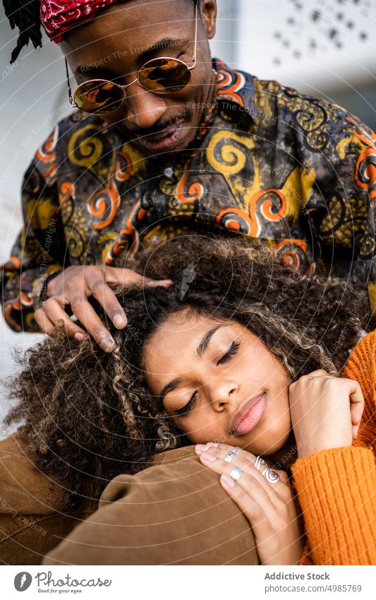 Black couple on bench on the street happy urban embrace cuddle date together ethnic black african american relationship rest dreadlocks style cool modern trendy