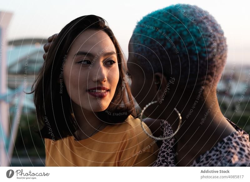 Multiracial lesbian couple sitting close together outdoors closeness relationship bonding love lgbt homosexual young multi ethnic multiracial asian female