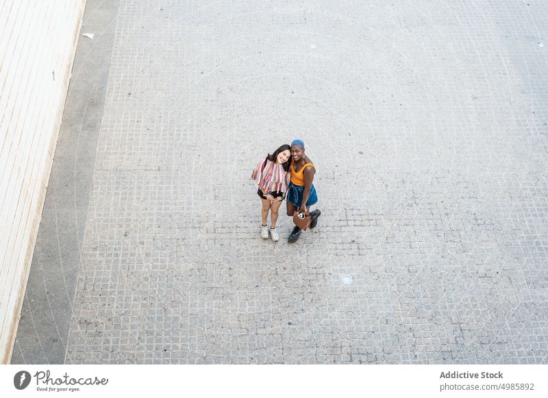 Stylish multiethnic couple of lesbian women in city cool urban style lgbt smile cheerful positive same sex girlfriend street multiracial diverse black