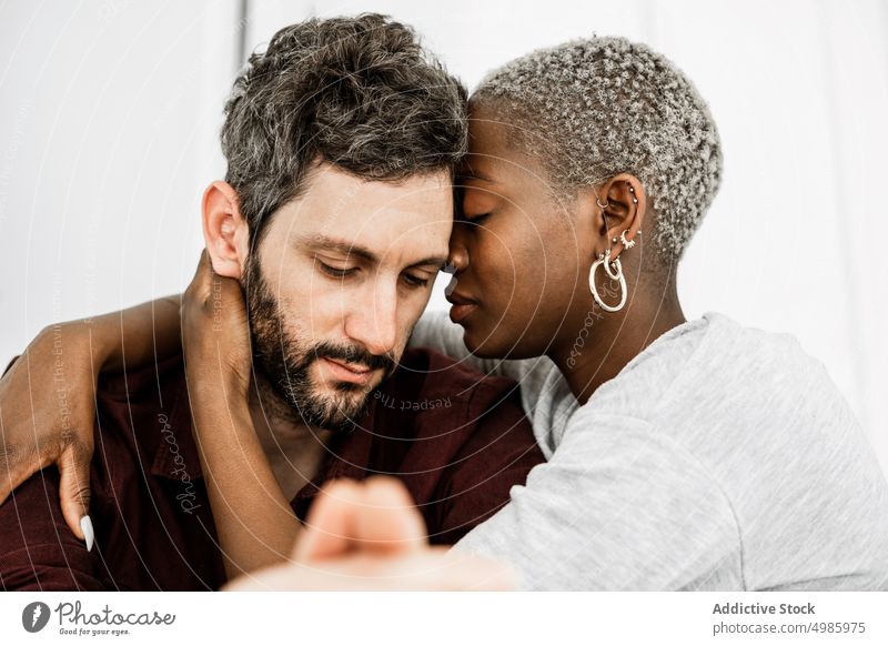 Carefree multiethnic lovers in embrace couple hug cuddle home relationship sit table kitchen modern casual together romantic affection african american black