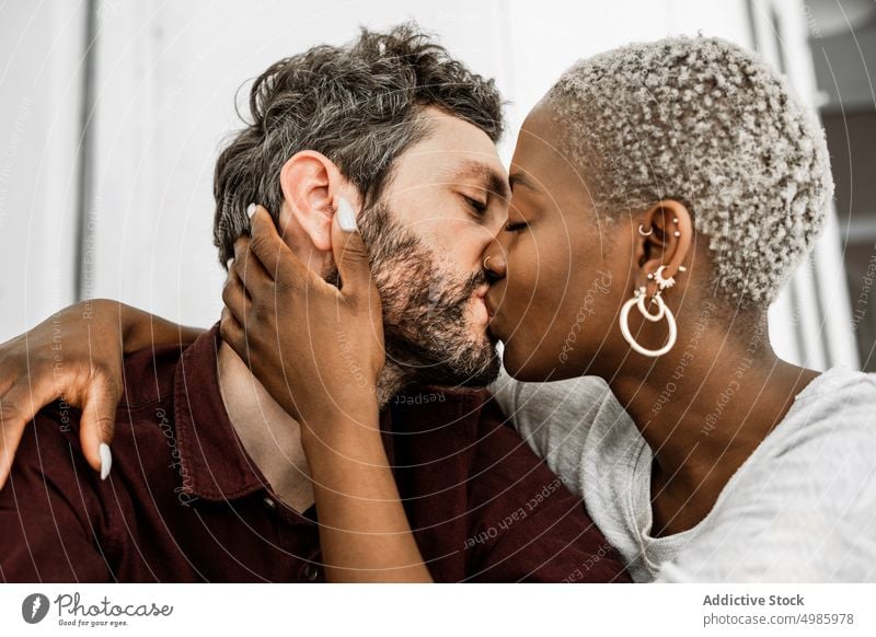 Young multiethnic lovers during tender kiss at table couple home relationship casual sit hug cuddle embrace together romantic affection african american black