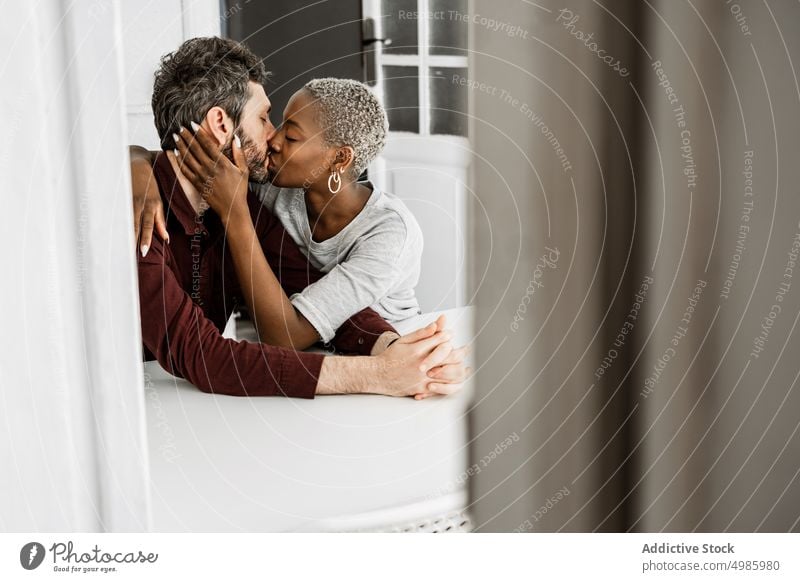 Young multiethnic lovers during tender kiss at table couple home relationship casual sit hug cuddle embrace together romantic affection african american black