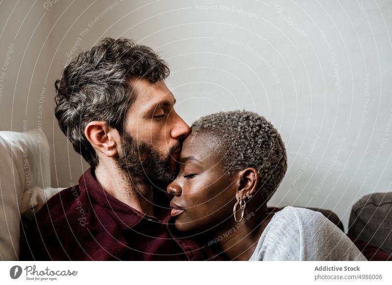 Young multiethnic couple resting on sofa cuddle couch asleep harmony calm home love relax living room bonding relationship hug leisure embrace together romantic