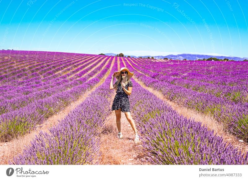 Close up of a young girl in a floral dress with a hat on her head between lavender in southern Provence Valensole France beautiful beauty brunette caucasian