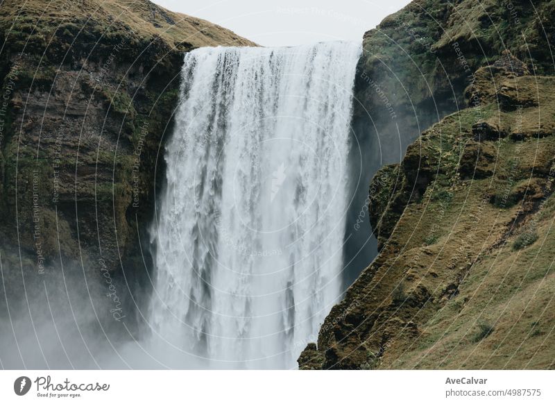 Massive skofagoss waterfall at Iceland Island during a foggy rainy day, nature landscape. Dark tones stream wet people popular rock scenic alone conservation