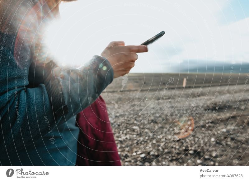 Young woman traveler checking writing on smart phone during sunset day at Iceland, close up image. connection horizontal journey one person sharing vacations