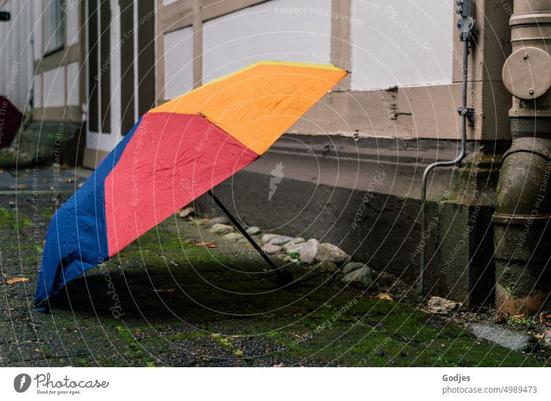 [HH Unnamed Road] Colorful umbrella stands stretched on the ground in front of a house wall Umbrella Ground Shadow variegated Wall (building) Exterior shot