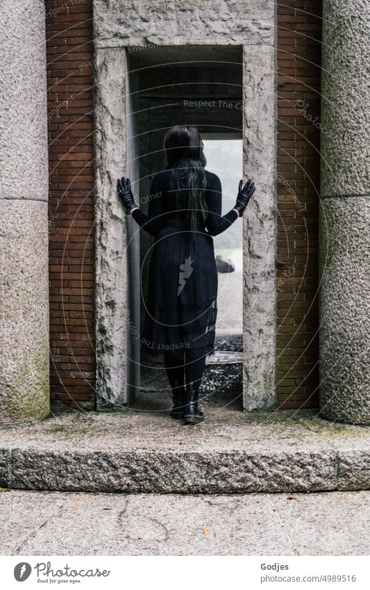 [HH Unnamed Road] Rear view of a woman dressed in black in the entrance of a memorial site. Woman commemoration Gothic style Black Grief Light Shadow