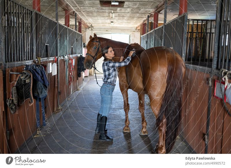 Woman taking care of her horse in stable Horse woman Ranch Saddle Stable One Person People Adult Barn animals Rural Scene Animal Trainer farm hobby