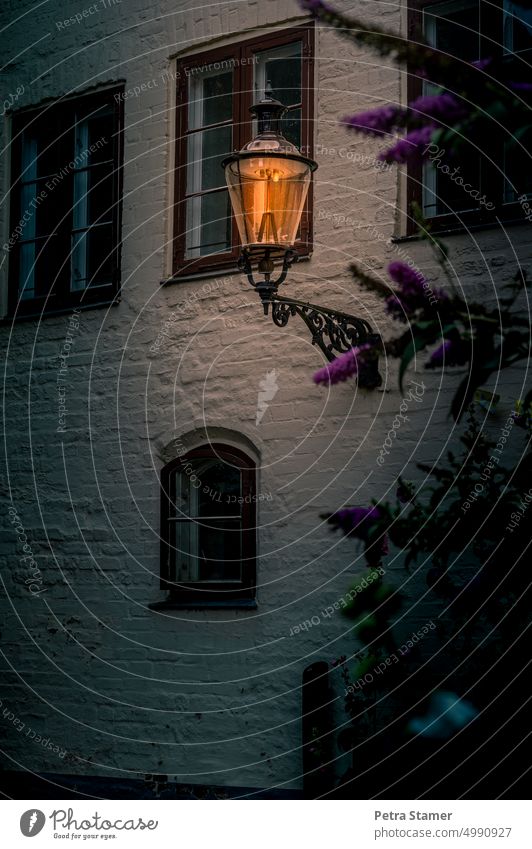 Nightlife | Shining lantern on a house wall Lantern Lamp stream Energy house facade Light Street lighting Lighting Glowing lantern Window Facade Architecture