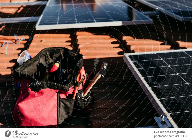 bag of technician tools and solar panel on roof during sunrise.Renewable energies and green energy concept solar panels photovoltaic self consumption engineer