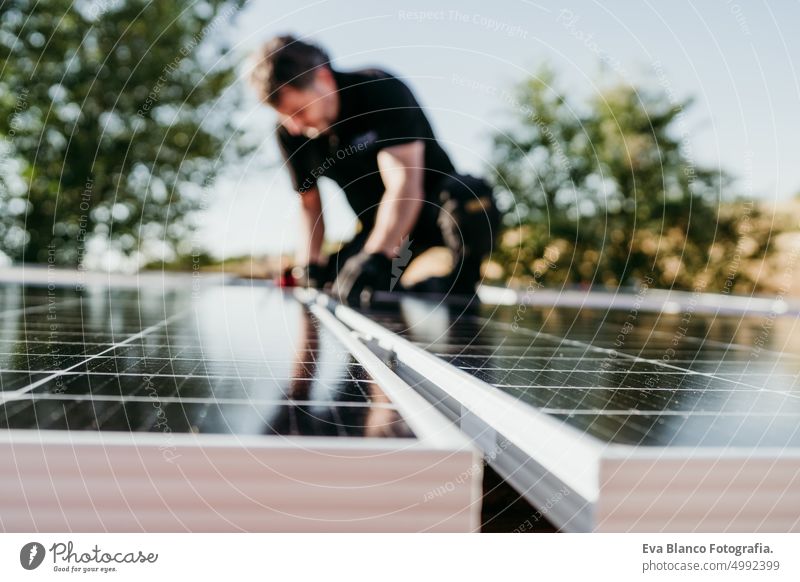 mature Technician man assembling solar panels on house roof for self consumption energy. Renewable energies and green energy concept. focus on foreground