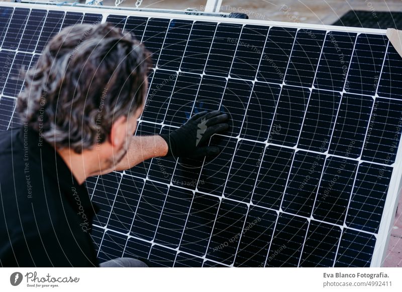 back view of mature Technician man checking solar panels for self consumption energy. Renewable energies and green energy concept technician roof photovoltaic