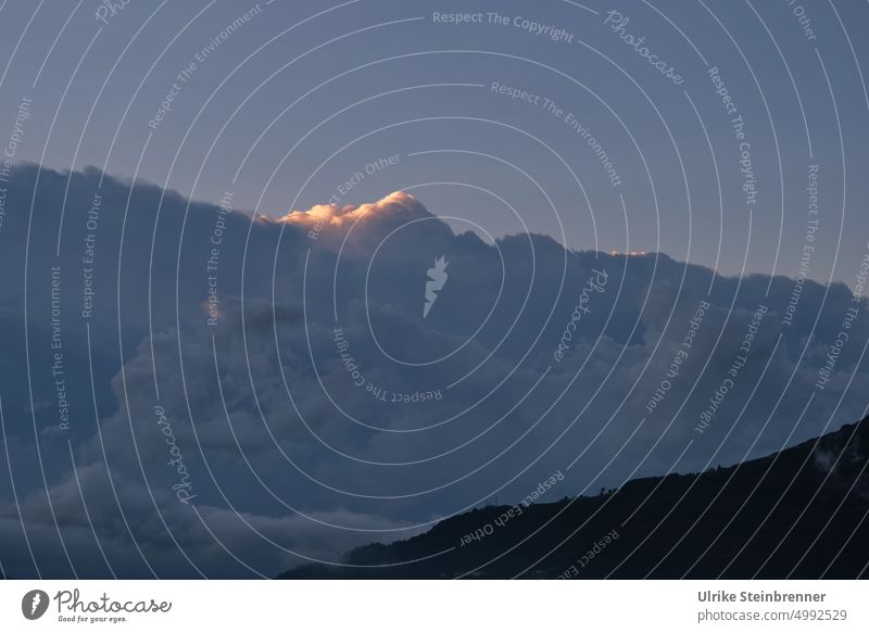 Bright spot above cloud mountain Storm somber Sky Clouds Light Eerie Bad weather Menacing Threat Bank of clouds Flare sunshine morning sky Sunrise