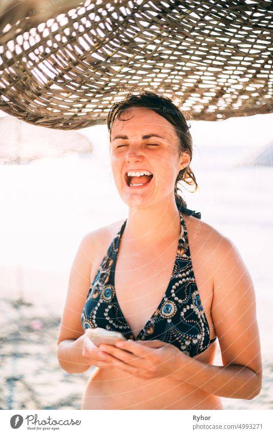 Young Caucasian Lady Woman Use Smartphone Under Beach Umbrella On Sunset. Vacation On Sea Ocean active lifestyle attractive authentic beach beautiful beauty