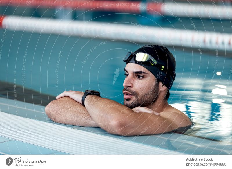 Swimmer in goggles leaning on poolside swimmer lean on hand masculine man portrait athlete sport macho tired accessory sportsman glad swimming modern