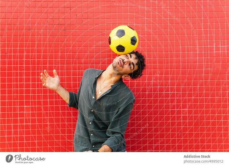 Hispanic male doing trick with football ball man balance street wall colorful bright weekend young hispanic ethnic juggle urban energy soccer modern casual