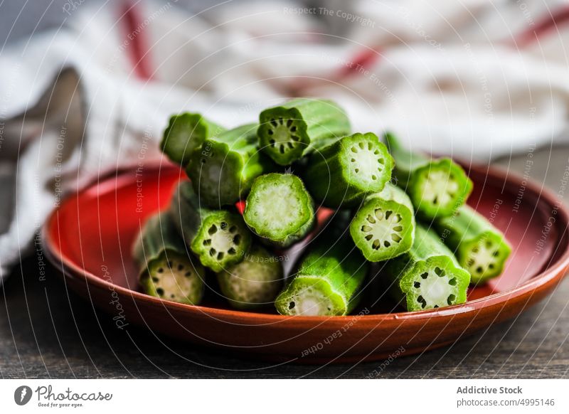 Red ceramic plate with stack of bamia slices okra bamya bowl cook cuisine cut diet food green healthy keto ketogenic low- carbs organic plant-based raw red