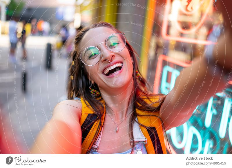 Funny female taking selfie on street woman happy funny modern urban grimace style young glasses weekend carefree cheerful backpack memory tourist traveler neon