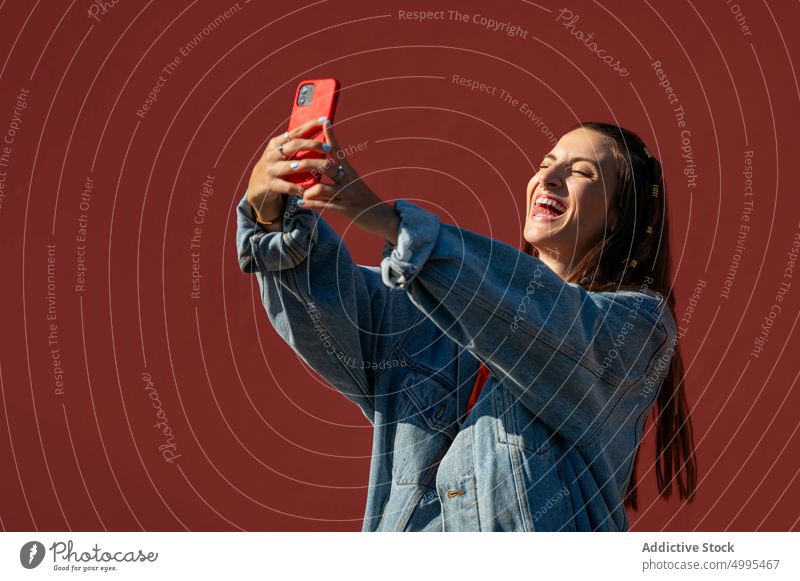 Young woman taking selfie on the street smile smartphone wall weekend happy bright female young style summer cellphone gadget cheerful modern carefree