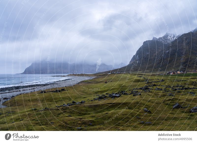 Small settlement at seaside near rocky mountains against overcast sky nature winter houses fjord village picturesque ridge landscape seashore Uttakleiv beach