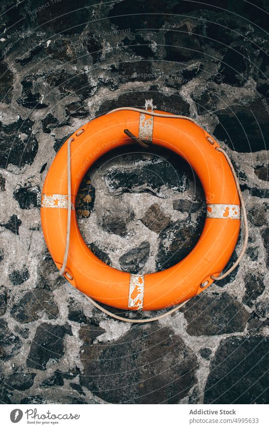 Lifebuoy on old stone wall lifebuoy hang beach shabby rough building protect ring la palma spain canary islands seaside peg weathered daytime orange tube float