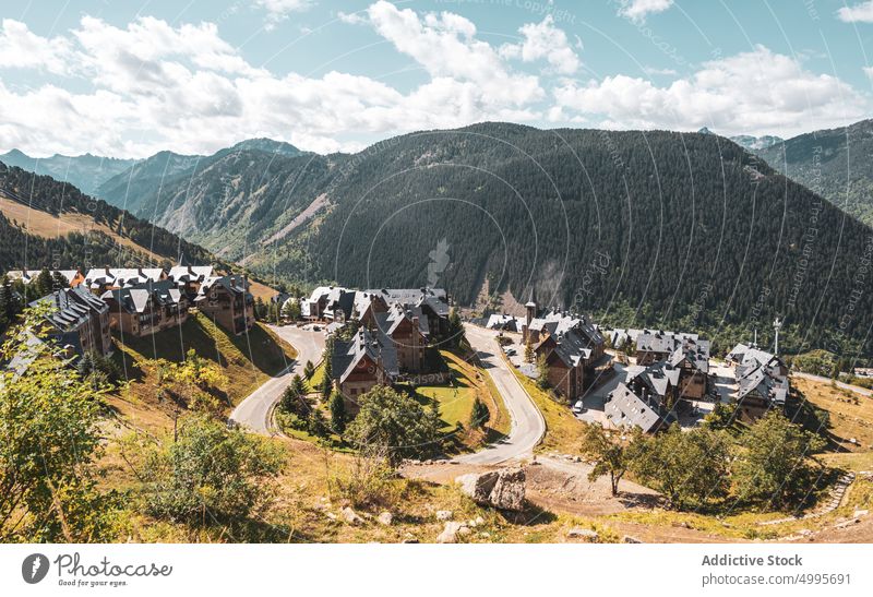 Scenic mountainous valley with small village under cloudy blue sky landscape nature highland countryside forest house road settlement picturesque asphalt